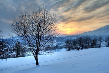 Winter sunset from snowy fields over italian alpine village