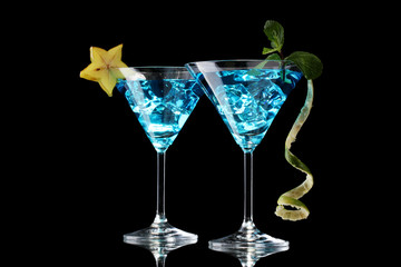 Blue cocktail in martini glasses on black background