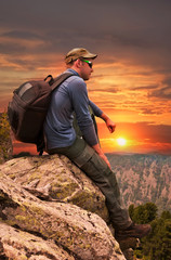 man -  tourist sits on a rock and admires a sunset