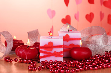 candles for Valentine's Day on wooden table on red background