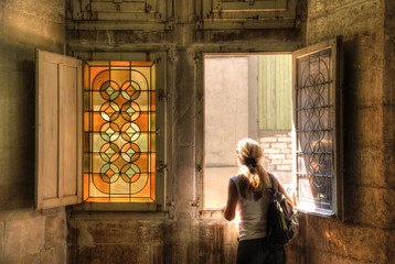 A girl seen from behind facing a stained glass window