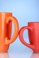 Two colored cups handles close-up on blue background