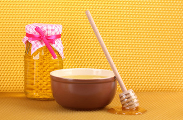 Jar of honey, bowl and wooden drizzler with honey