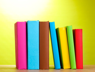 Books staying on wooden table on green background