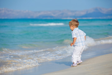 Fototapeta na wymiar Młoda ładny chłopiec grając szczęśliwie na pięknej plaży