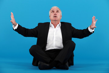 senior businessman sitting on the floor and looking upwards