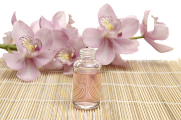 Fototapeta na wymiar Beautiful orchid and bottles with essential oil on bamboo mat