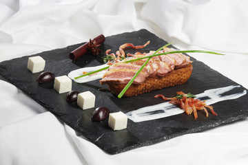 Entenbrust auf Graubrotcrostini mit  Röstspeck und Schmandwürfel
