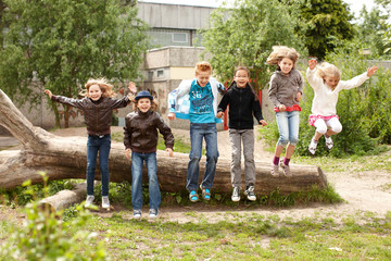 Gruppe Schulkinder springt von Baumstamm