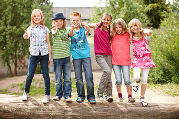 Fototapeta Gruppe fröhlicher Kinder auf Baumstamm obraz