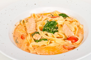 tasty pasta with cream, salmon, cheese and parsley close up