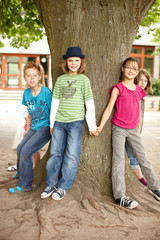 Obraz na płótnie Canvas Gruppe Kinder stellen sich um einen Baum