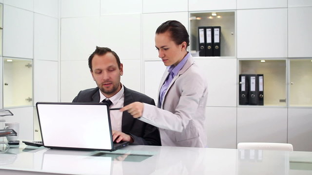 Businessman and businesswoman working with laptop in office