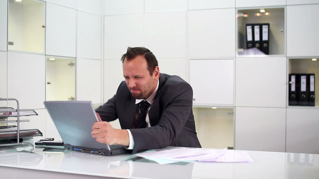 Angry businessman hitting and throw away laptop in the office