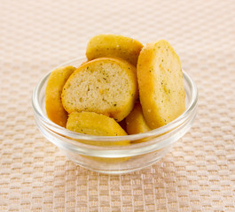 Appetizing rusks in bowl on beige napkin