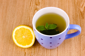 Mint tea with mint leaf and lemon on wooden background