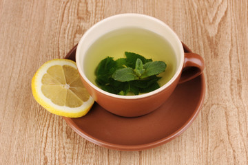 Mint tea with mint leaf and lemon on wooden background