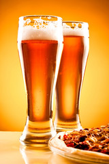 Two glass of beer and pizza over yellow background