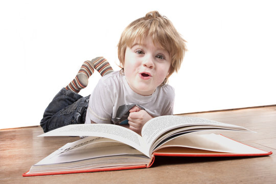 Boy Laying On Floor Pulling A Funny Face Whilst Reading Book