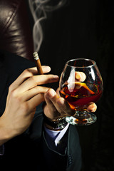 Brandy Glass at male hand, smoking cigar