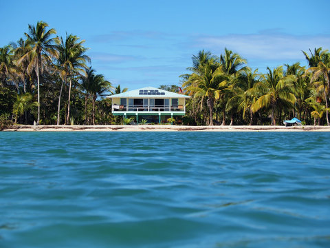Tropical off grid beach house with solar panels seen from the sea