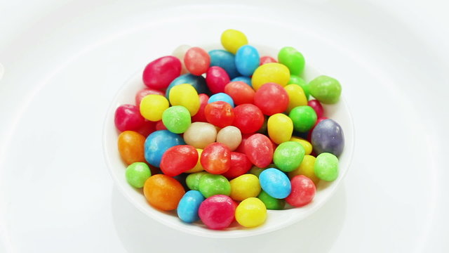 Multicolor bonbon sweets (ball candies) rotating on white plate