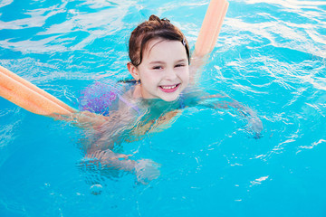 Girl enjoys summer day in swimming pool.