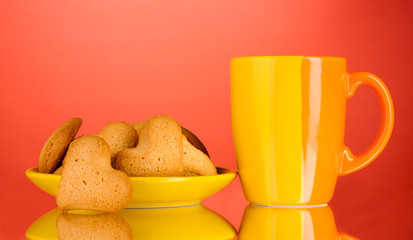 Heart-shaped cookies on yellow plate and cup on red background