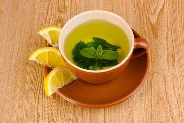 Mint tea with mint leaf and lemon on wooden background
