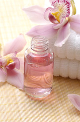 spa essentials- white towel, orchid flowers and massage lotion