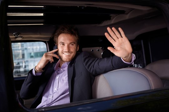 Celebrity waving from limousine window smiling