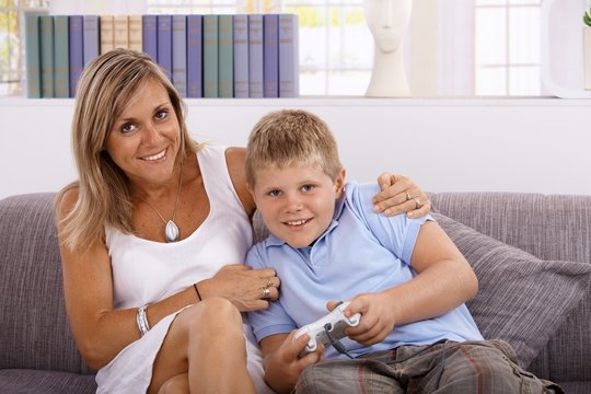 Little boy and mother playing video game smiling