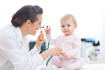 Obraz na płótnie Canvas Pediatrician doctor playing with baby on examination