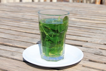 Tea with fresh mint on wooden table on the beach