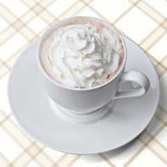 Tasse Kakao mit Sahnehäubchen auf Karodecke