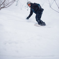 Fototapeta na wymiar Young man freeride snowboarding off-piste in a mountain resort