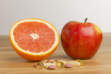 Nahrungsergänzungsmittel vs.Orange und Apfel