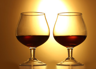 Two glasses of cognac on yellow background