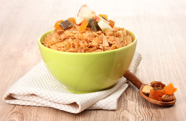 tasty cornflakes in bowl with dried fruits on wooden table