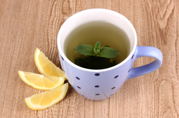 Mint tea with mint leaf and lemon on wooden background