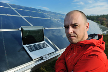 engineer using laptop at solar panels plant field