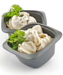 Meat pelmeni with sour cream and greens in black bowls isolated