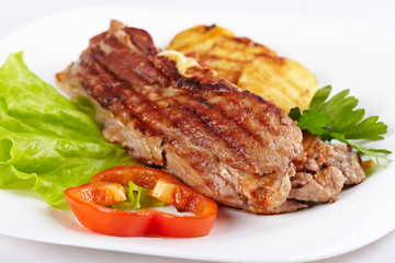 Grilled meat with vegetables on white plate