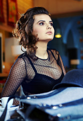 Fototapeta premium Charming sexy woman in black clothes sits at magnificent cafe