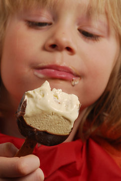 Niña comiendo una paleta de helado de chocolate y vainilla.