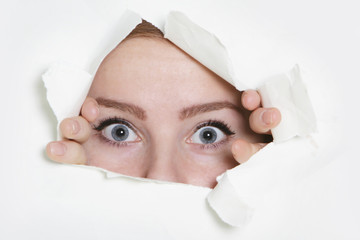 woman peeping through hole in paper