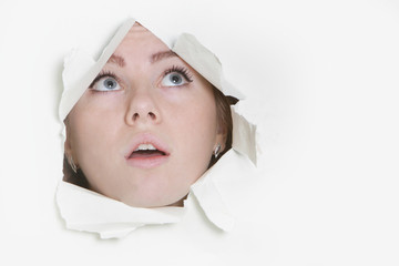 young woman peeping through hole in paper