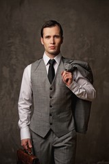 Businessman with a briefcase on grey background.