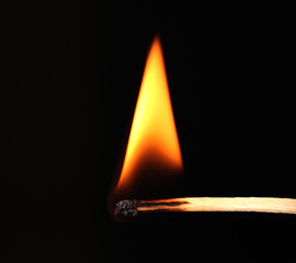 Burning match on black background