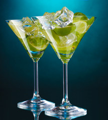 glasses of cocktails with lime and mint on blue background